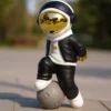 casual astronaut sculpture – black & white design with gold helmet on planet base